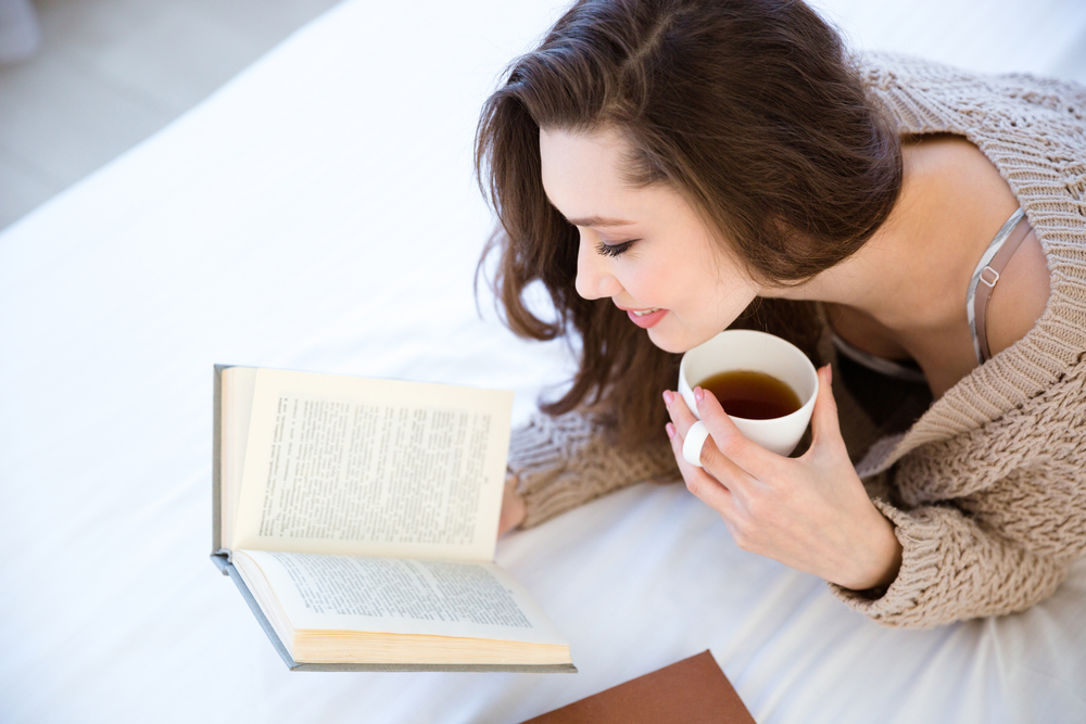 Woman reading  a book with coffee in hand