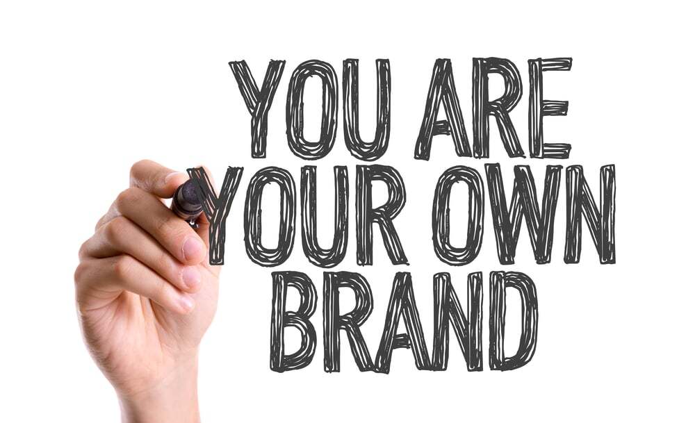 Image showing someone writing on a transparent surface: You are your own brand
